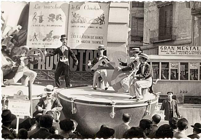 Tranvía que llega desde una callejuela justo detrás de una falla, en servicio.