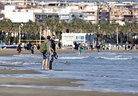 Dos turistas se mojan los pies en la playa de la Malvarrosa este domingo.