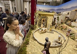 Marta Mercader, fallera mayor infantil de Valencia, y su corte de honor contemplan el belén del Salón de Cristal.