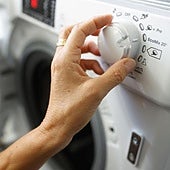 Una mujer programa una lavadora.