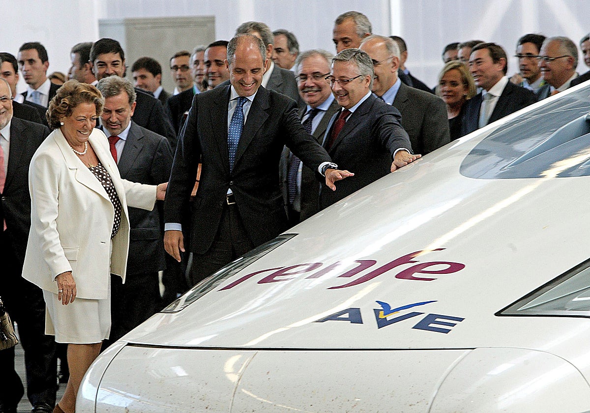 Rita Barberá y Francisco Camps, entre otros, observan el AVE tras su viaje inaugural a Valencia.