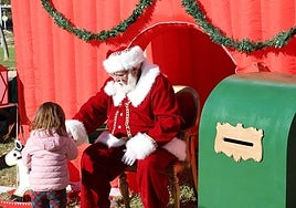 Papa Noel atiende a una niña junto al buzón para la carta de los regalos.
