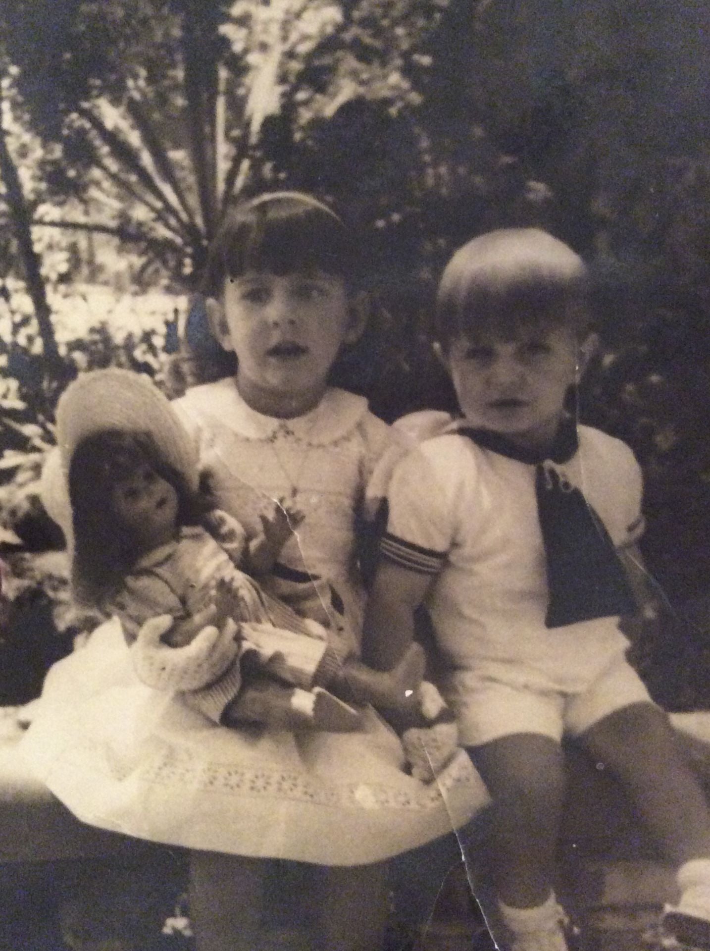 Con una de sus muñecas y su hermano.