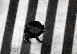 Un hombre pasea bajo la lluvia en Valencia.