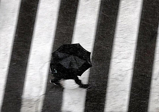 Un hombre pasea bajo la lluvia en Valencia.