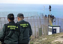 Un grupo de inmigrantes, encaramados a la valla en Melilla. / N. RAMOS (EFE)