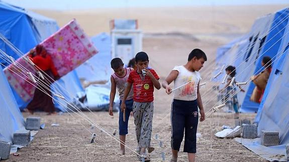 Un grupo de niños iraquíes caminan por un campamento de refugiados