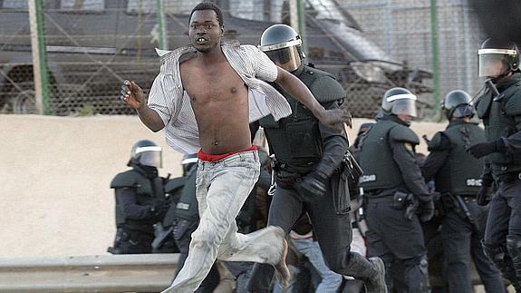 Agentes de la Guardia Civil intentan detener a un inmigrante tras saltar la valla de Melilla. 