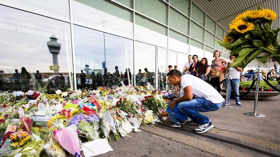Varias personas depositan una corona de flores en el monumento conmemorativo a las víctimas. 