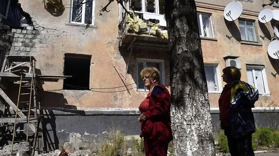 Dos personas frente a un edificio a 15 kilómetros de Donetsk.