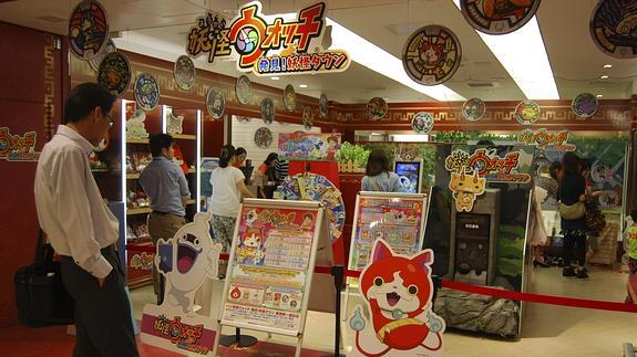 Un grupo de personas se detienen a mirar el interior de Yo-Kai Watch Town. 
