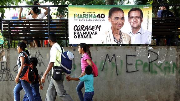 Un grupo de personas pasa delante de un cartel de la candidata Marina Silva. 