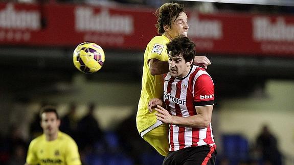 Dos jugadores saltan por el balón. 