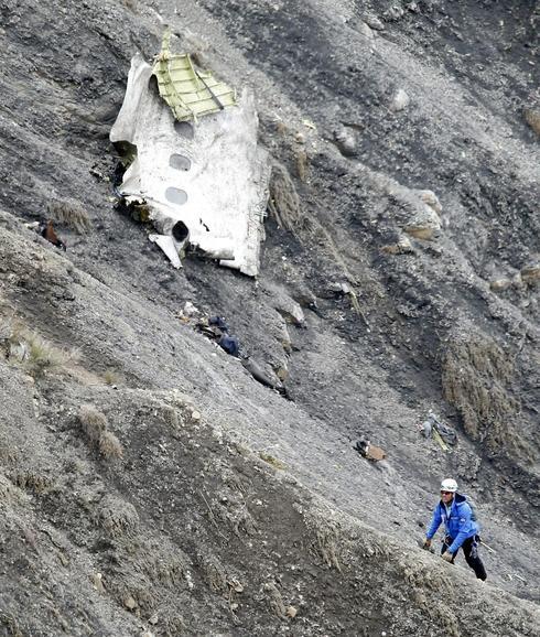 Un miembro de los servicios de rescate, al lado de un tramo de fuselaje del avión siniestrado. 