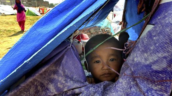 Un niño nepalí se asoma desde el interior de una tienda de campaña en la zona de Bodha. 