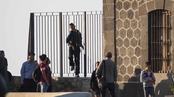 Un grupo de menores sale de los acantilados por entre las rejas mientras los agentes intentan sacar el cuerpo de su compañero.