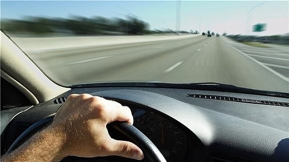 Un hombre, conduciendo su vehículo por una autopista durante sus vacaciones. 