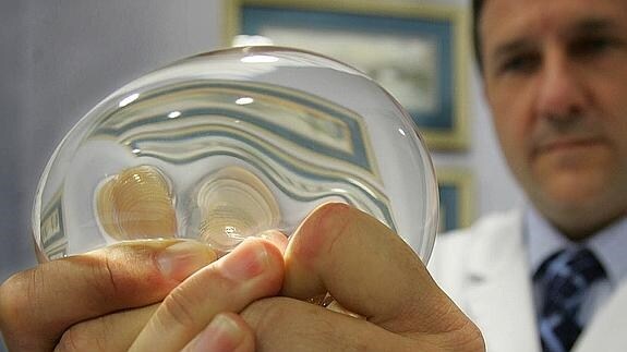 Un cirujano plástico muestra un implante de silicona. 