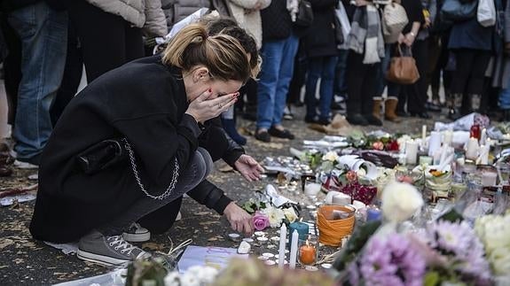 Varias personas colocan flores y velas en memoria de las víctinas de París.