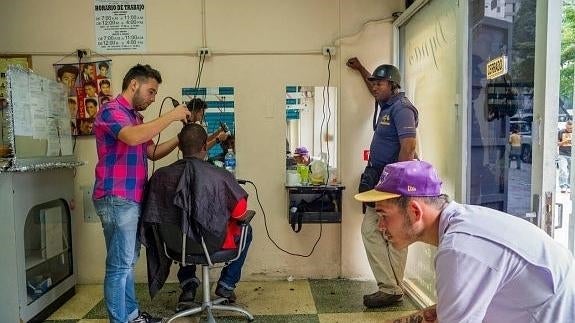 Unos jóvenes aguardan para cortarse el pelo en una barbería de Caracas. 