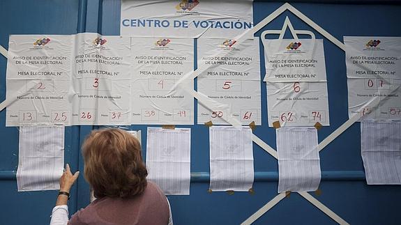 Una mujer consulta las listas de un centro de votación de Caracas.