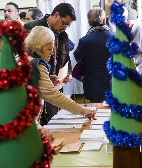 Una mujer elige sus papeletas en un colegio electoral del barrio sevillano de Triana.