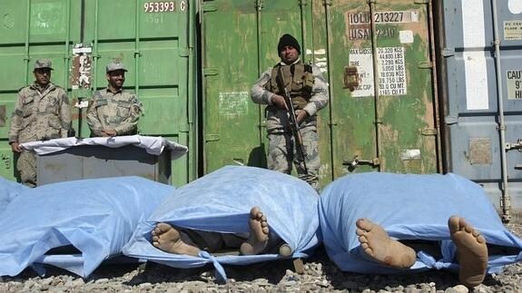 Agentes de policía afganos custodian los cuerpos de cinco inmigrantes.  
