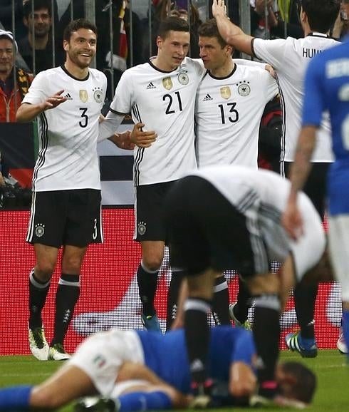 Los futbolistas alemanes celebran un gol mientras un italiano permanece en el suelo. 