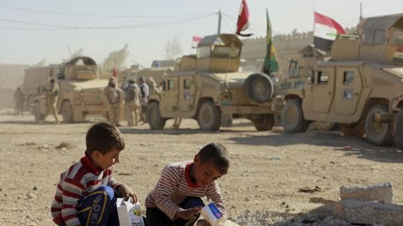Dos niños juegan ante los vehículos militares del Ejército de Irak.