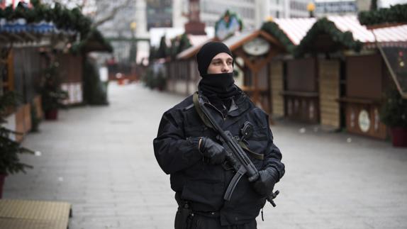 Un agente de policía alemán permanece en guardia en un mercadillo navideño, en la Breitscheidplatz de Berlín. 