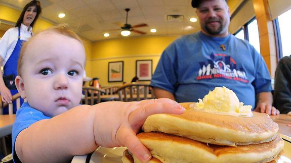Bebé de ocho meses pone su mano sobre una pila de tortitas.