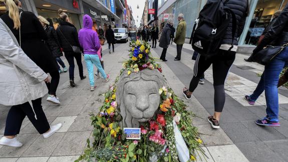 arias personas caminan junto a un memorial improvisado en la calle peatonal de Drottninggatan.