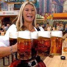 Una camarera con ocho jarras de cerveza.