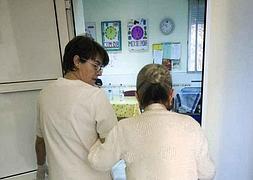 Una auxiliar acompaña a una anciana. / EFE