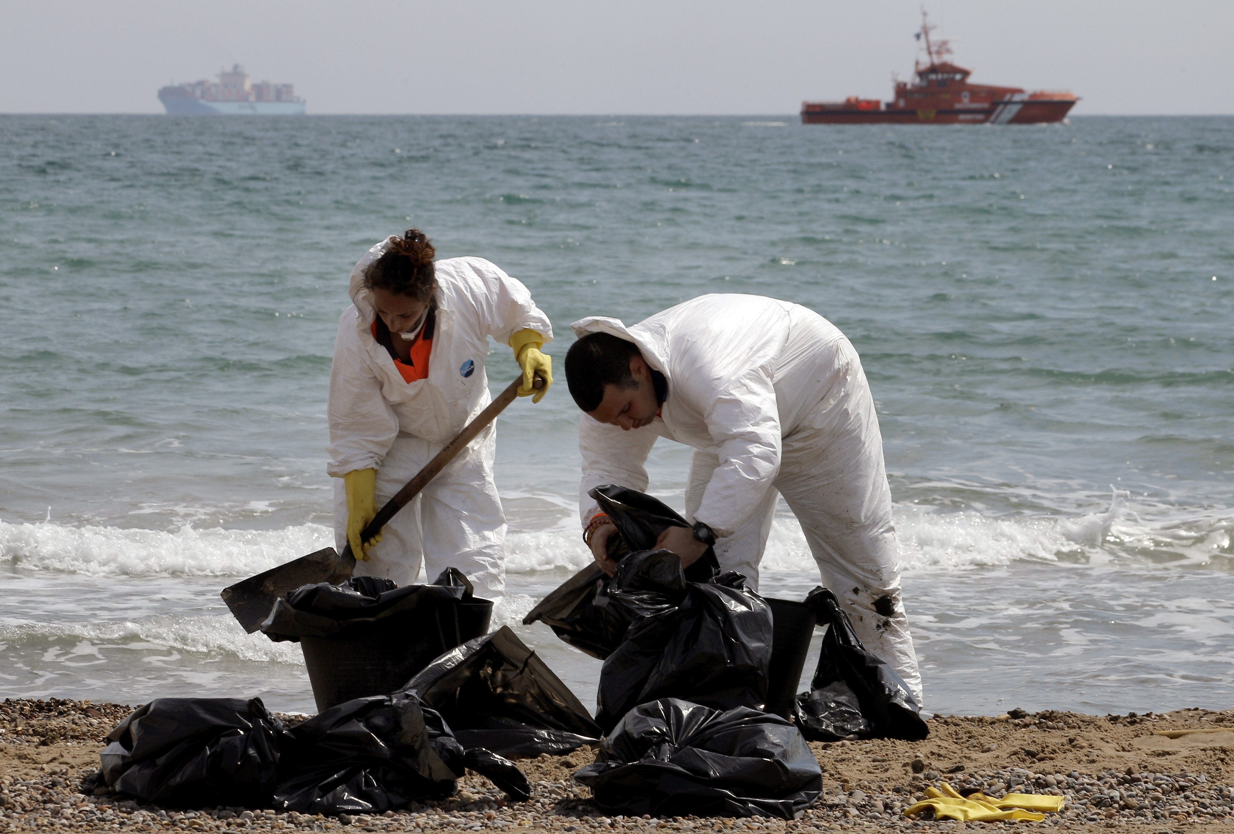 Dos trabajadores recogen el vertido.