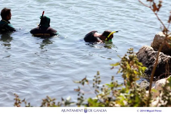 Tres buzos de la Guardia Civil rastrean, ayer, la desembocadura del río Serpis. 