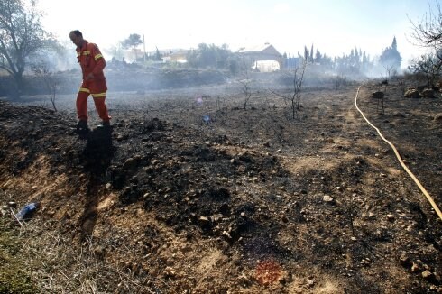 Un bombero camina sobre los restos de un reciente incendio en Godelleta. :: irene marsilla
