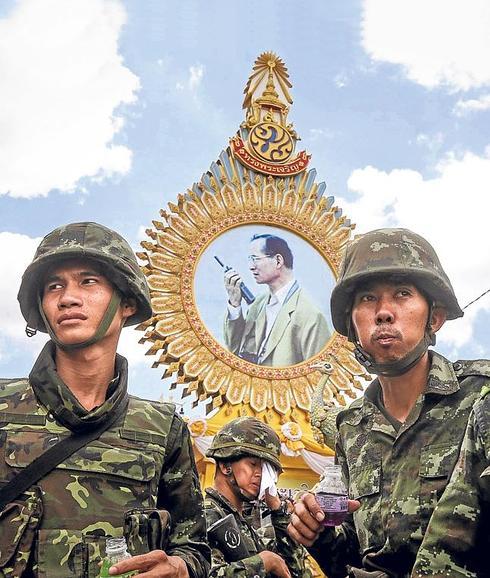 Soldados tailandeses desplegados en las calles de Bangkok, junto a una fotografía del rey Bhumibol. 