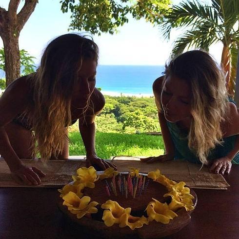 Gisele y Patricia Bündchen soplando la tarta de cumpleaños de la primera.