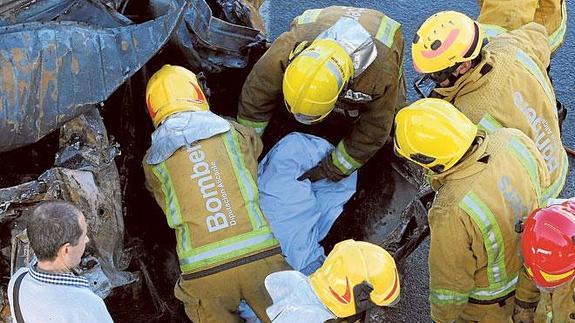 Los bomberos, extrayendo un cadáver de la furgoneta calcina.