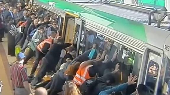 Decenas de personas empujando el vagón para liberar al hombre atrapado.