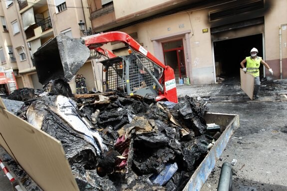 Un operario traslada a un contenedor los restos del incendio que ayer obligó a desalojar cuatro edificios ayer en Valencia