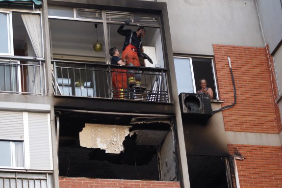 Dos bomberos y una vecina, ayer, en la fachada quemada del edificio. :: damián torres