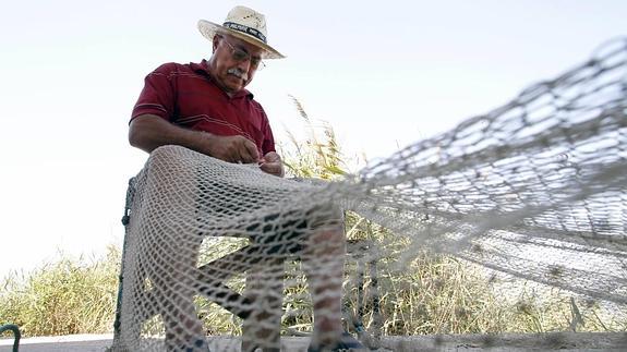 Un pescador remienda sus redes.