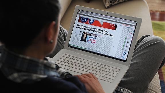 Una mujer lee la prensa desde su portatil.