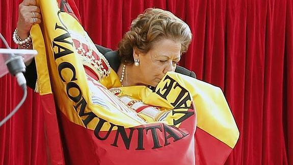 La alcaldesa de Valencia, Rita Barberá, madrina de la celebración, besando una bandera de España con una leyenda osbre la Comunitat Valenciana.