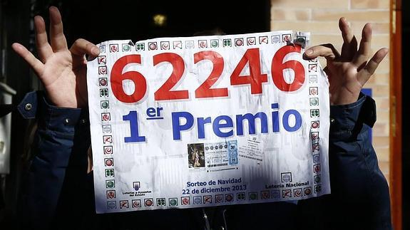 Hombre sostiene una reproducción del décimo premiado con el gordo en 2013.