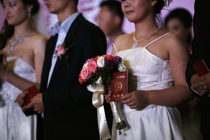 Novios sostienen su certificado de matrimonio durante una boda colectiva en Shanghai. 