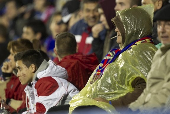 Un aficionado se protege de la lluvia. :: damián torres