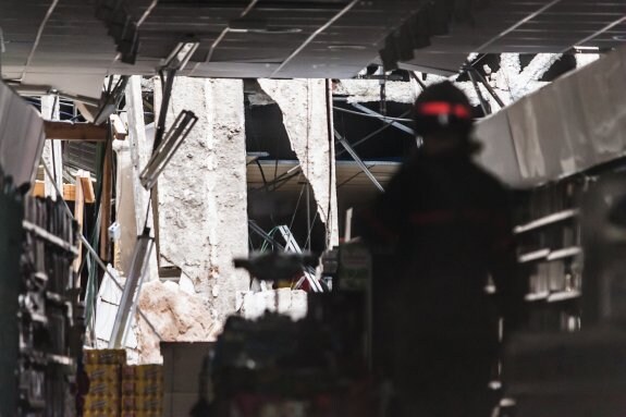 Un bombero comprueba los desperfectos en el supermercado a causa del hundimiento del techo. :: jesús montañana